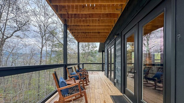 A wooden deck with rocking chairs and a glass door leading to a deck area.