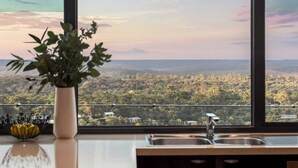 A kitchen with a large window overlooking a forested landscape. - On Top of the World S (Anglesea)