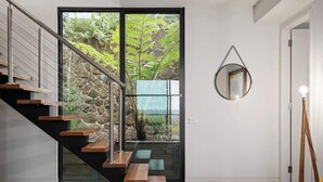 A modern staircase with wooden steps and glass railings, leading to a door with a glass panel. - On Top of the World S (Anglesea)