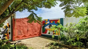 A courtyard with a red gate, a colorful mural, and a bicycle. - Beautiful 2-bed House in Nungwi (Nungwi)