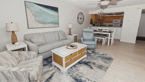A living room with a grey sofa, a striped armchair, a white coffee table, and a ceiling fan. - BH 402D Beautiful Views from this 2 bed/2 bath (Miramar Beach)