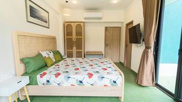 Ein Schlafzimmer mit Bett, Schreibtisch, Fernseher und einer Schiebetür.