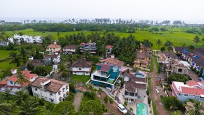 Una zona residencial con casas, algunas con piscinas, rodeada de vegetación y palmeras.