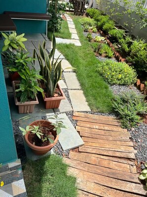 A garden pathway with potted plants and a wooden deck. - BRAND NEW VILLA LARGE POOL 5 STAR AMENITIES WALKING DISTANCE TO  BEAUTIFUL BEACH (Btalbhati)