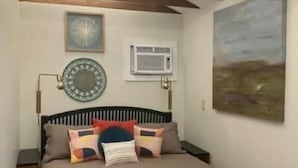 Une chambre à coucher avec un lit, une horloge murale, un appareil de climatisation et un tableau.