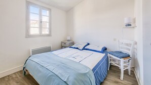 A bedroom with a bed, a chair, a nightstand, and a window. - Loix- Ré Island- House for 5 (Loix)