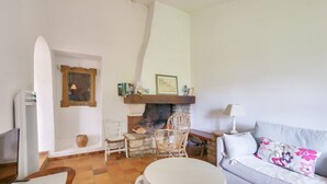 A living room with a fireplace, white furniture, and a tiled floor. - Loix- Ré Island- House for 5 (Loix)