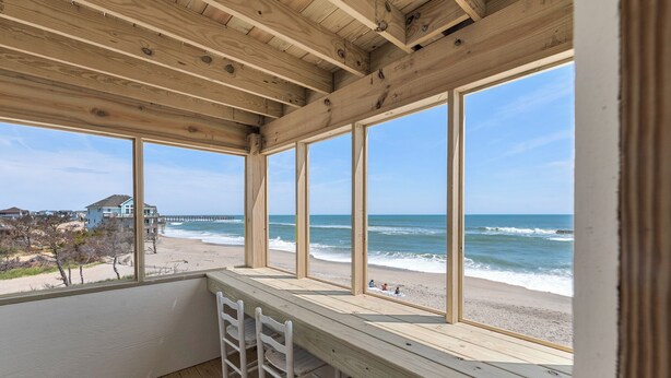 Una terraza de madera con vista a la playa y al océano.