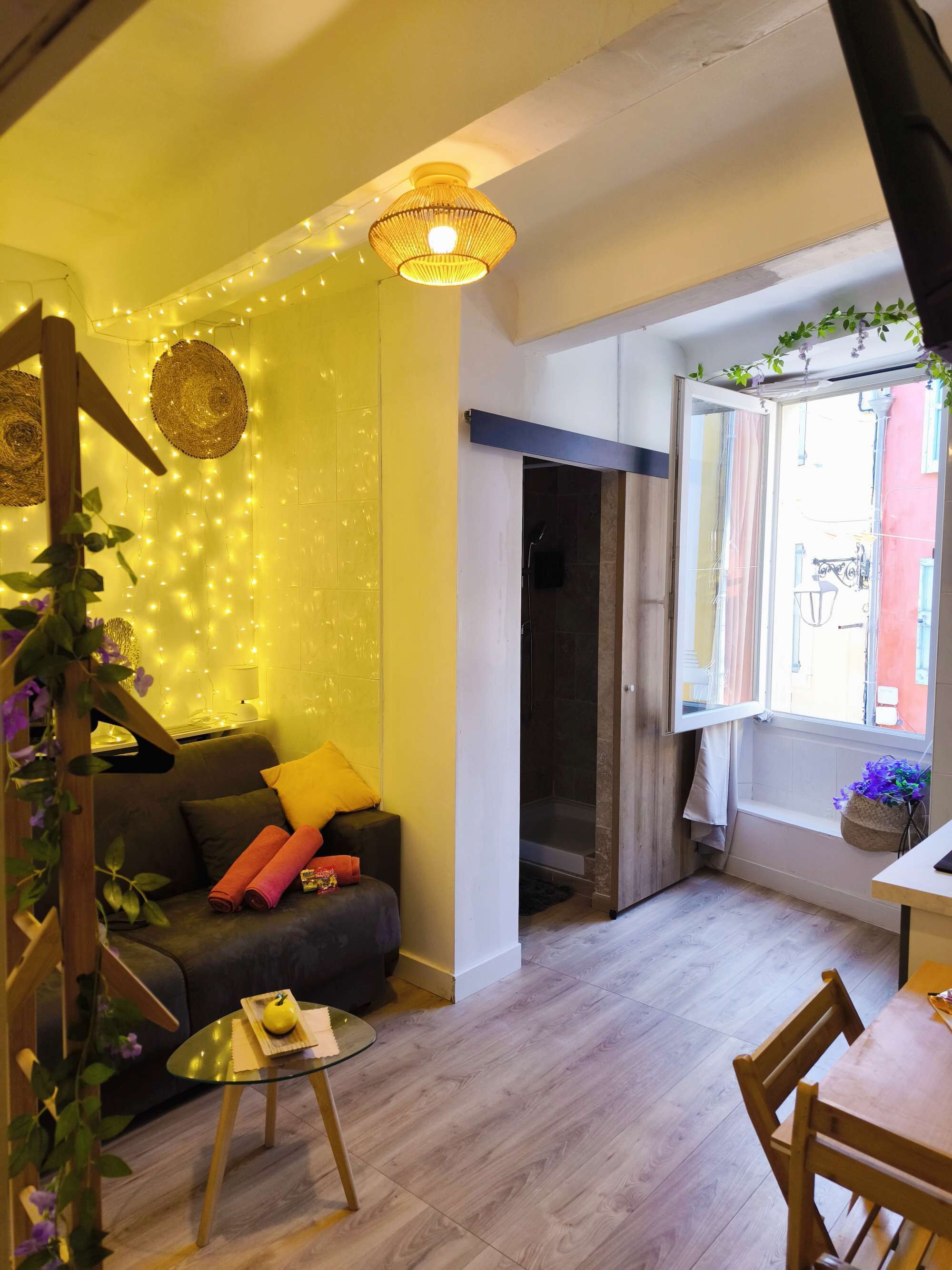 Ein gemütliches Zimmer mit einer Couch, einem kleinen Tisch, einem Fenster mit Blick und einer Deckenleuchte.