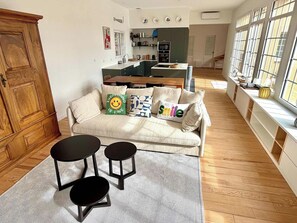 Ein Wohnzimmer mit einer Couch, zwei schwarzen Beistelltischen, einem gemusterten Teppich und einem Holzkabinett.