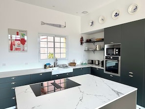 A modern kitchen with a marble island, dark cabinetry, and a window with a view. - House with garden in heart of Lacanau-Océan G0247 (Lacanau-Ocean)