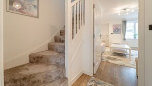 A staircase with carpeted steps leading to a room with a white bench and a table.