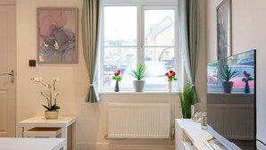 A modern bathroom with a window, radiator, and a mirror.