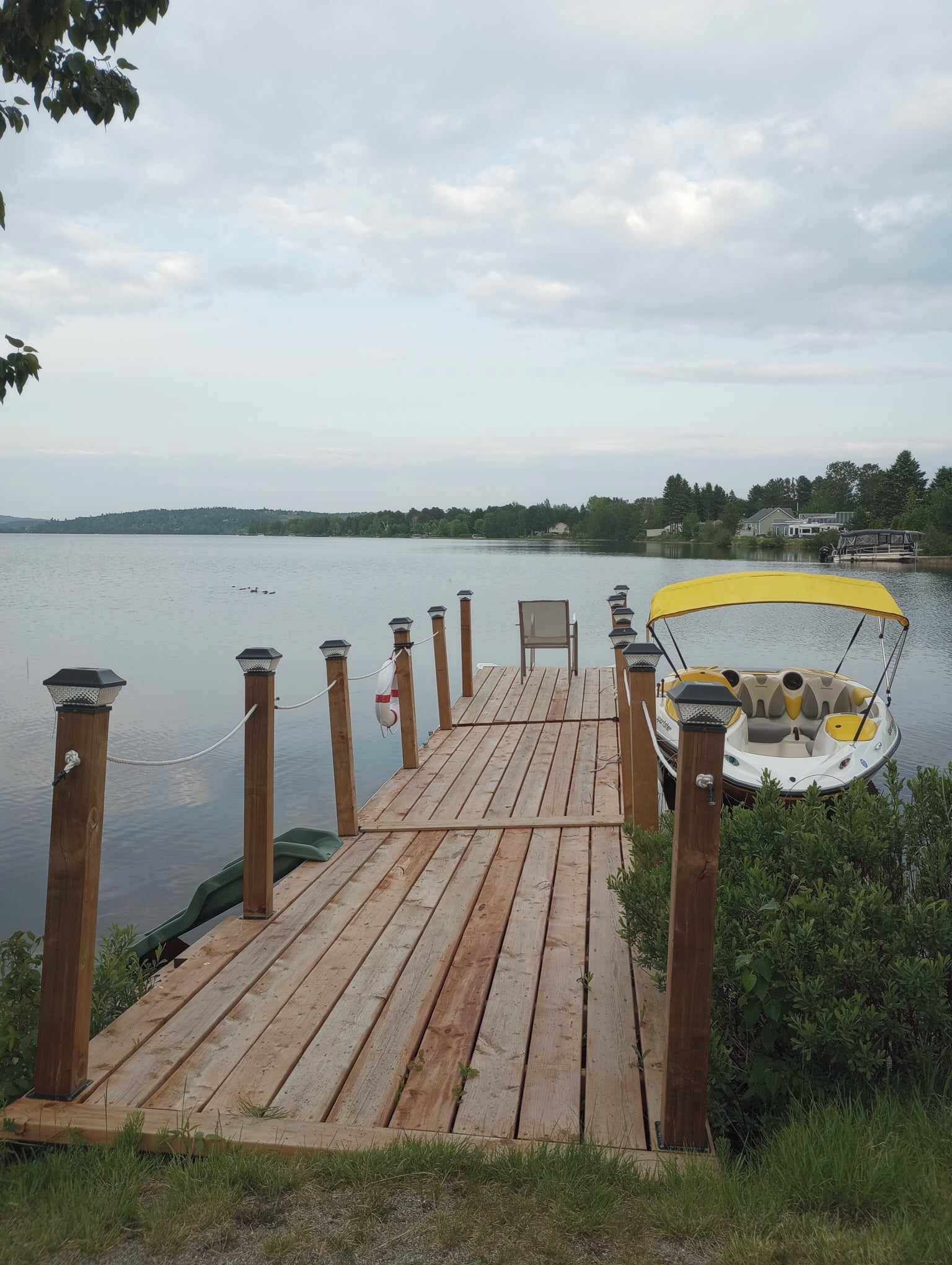 A wooden dock extending into a lake with a yellow canopy boat at the end.