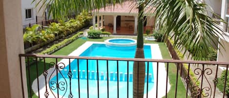 A swimming pool with a surrounding garden and a building in the background.