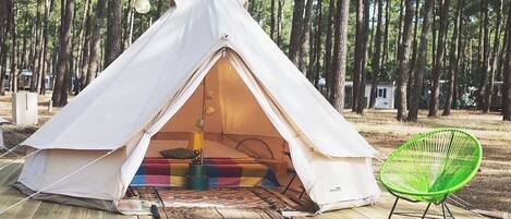 A white tent with a colorful interior, a green chair, and a wooden deck.