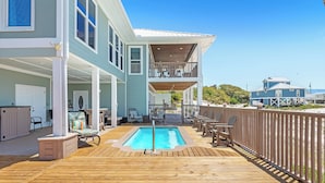 Una casa a due piani con una veranda in legno, una piscina e un balcone.
