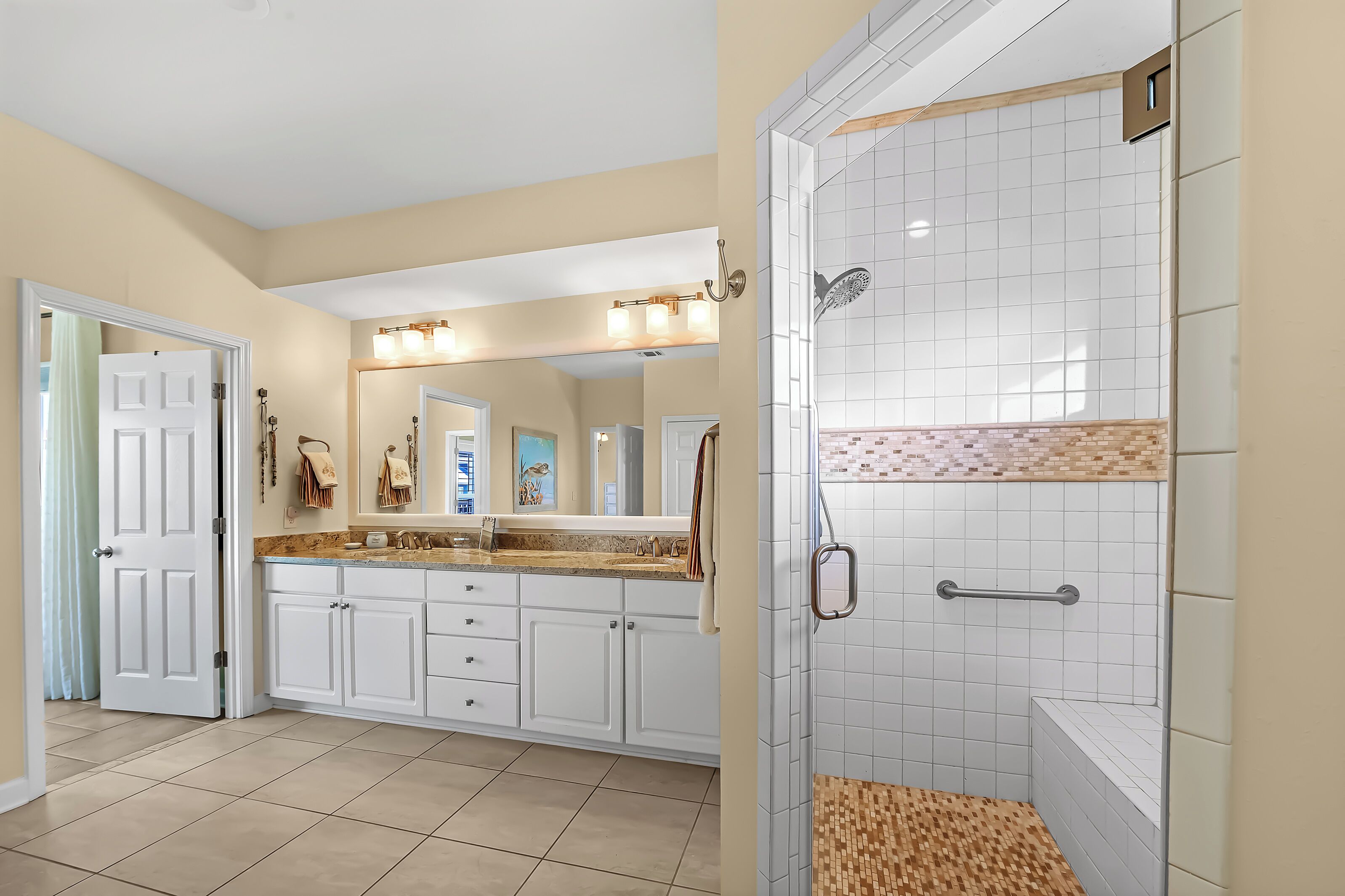 A modern bathroom with a walk-in shower, a vanity with a large mirror, and a tiled floor.