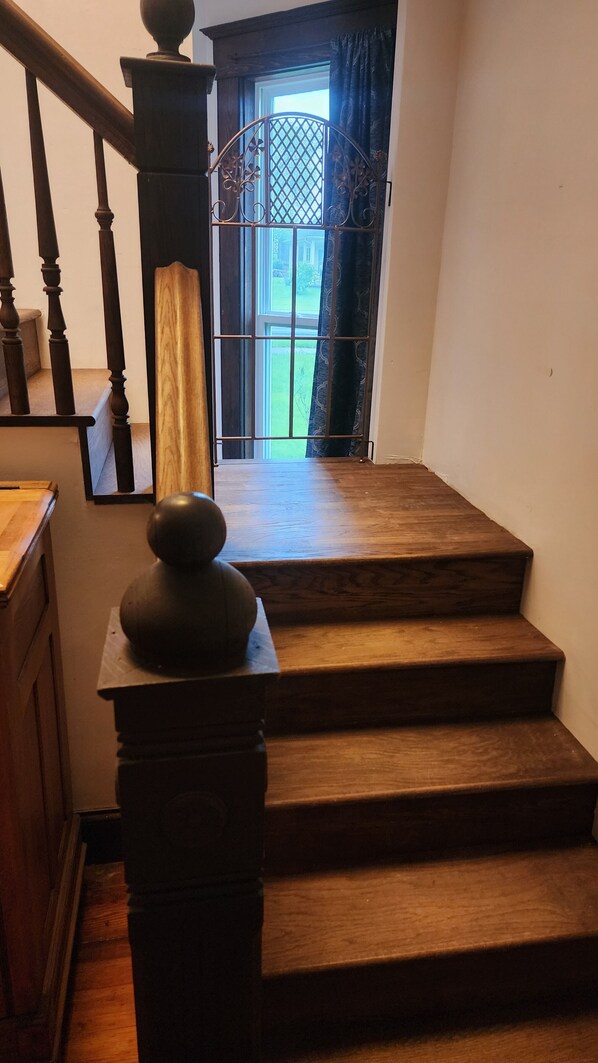 A wooden staircase with a balustrade leading to a door with a metal grille. - A real charmer built in 1915 , pet friendly , located next to Mark Twain lake. (Perry)