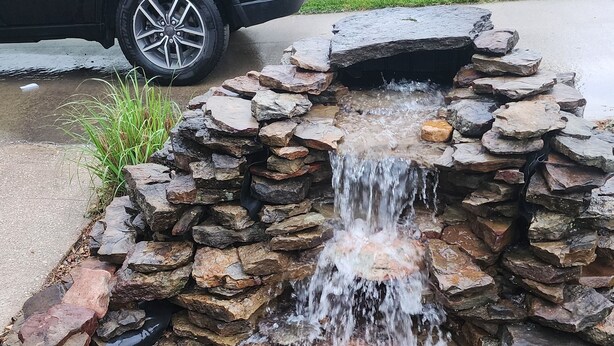A stone water feature with a waterfall, surrounded by a variety of rocks and pebbles. - A real charmer built in 1915 , pet friendly , located next to  Mark Twain lake. (Perry)