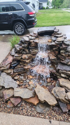 A stone water feature with a waterfall, surrounded by a variety of rocks and pebbles. - A real charmer built in 1915 , pet friendly , located next to Mark Twain lake. (Perry)