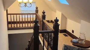 A spacious attic with a sloped ceiling, a wooden staircase with balusters, a chandelier, and a skylight. - A real charmer built in 1915 , pet friendly , located next to  Mark Twain lake. (Perry)