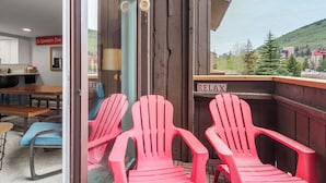 A room with a wooden bench, a red chair, and a view of a mountain.