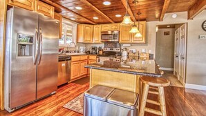 A modern kitchen with wooden cabinets, stainless steel appliances, and a central island. - Winter Hawk House (Groveland)