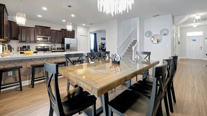 Een moderne keuken met donkerhouten kasten, een centraal eiland met zitplaatsen en een kroonluchter.