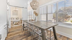 Une cuisine moderne avec une table en bois, des tabourets de bar et un lustre.