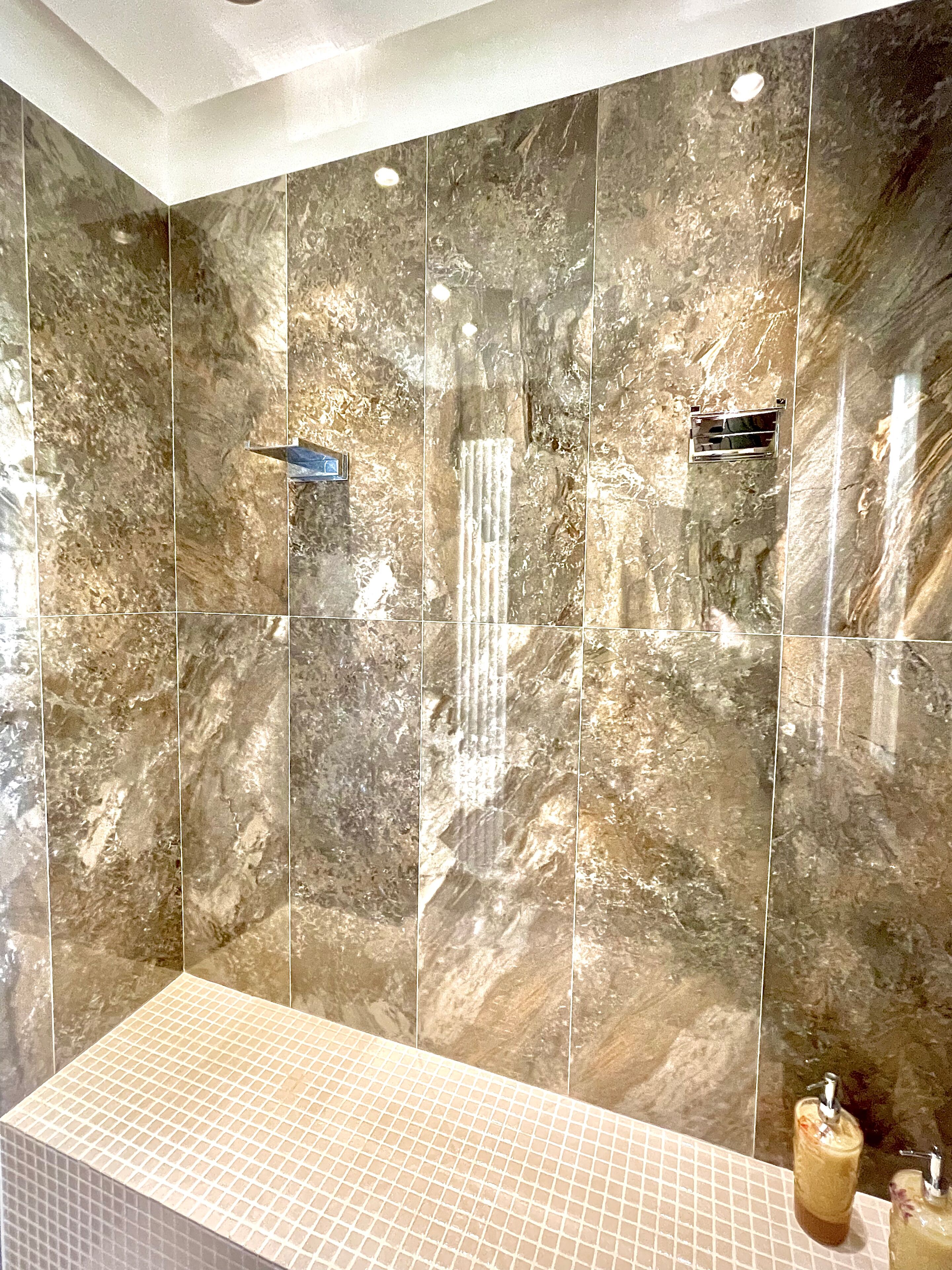 A bathroom with a large mirror, a sink, and a shower area.