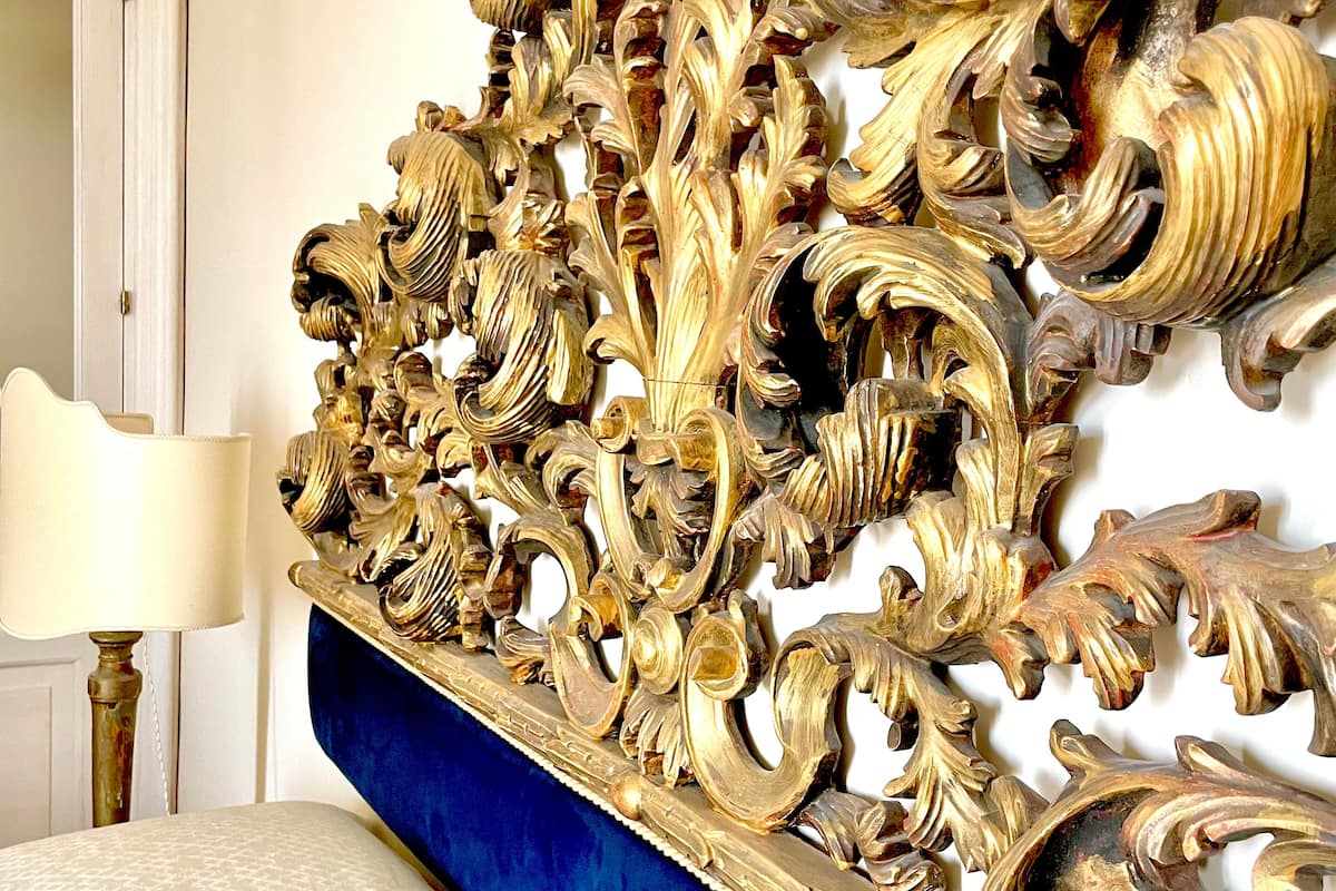 A bed with a blue upholstered headboard and a decorative gold headboard.