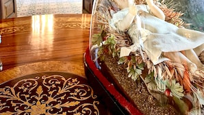Una habitación con una cama, una araña y una cúpula de vidrio decorativa con una figura.