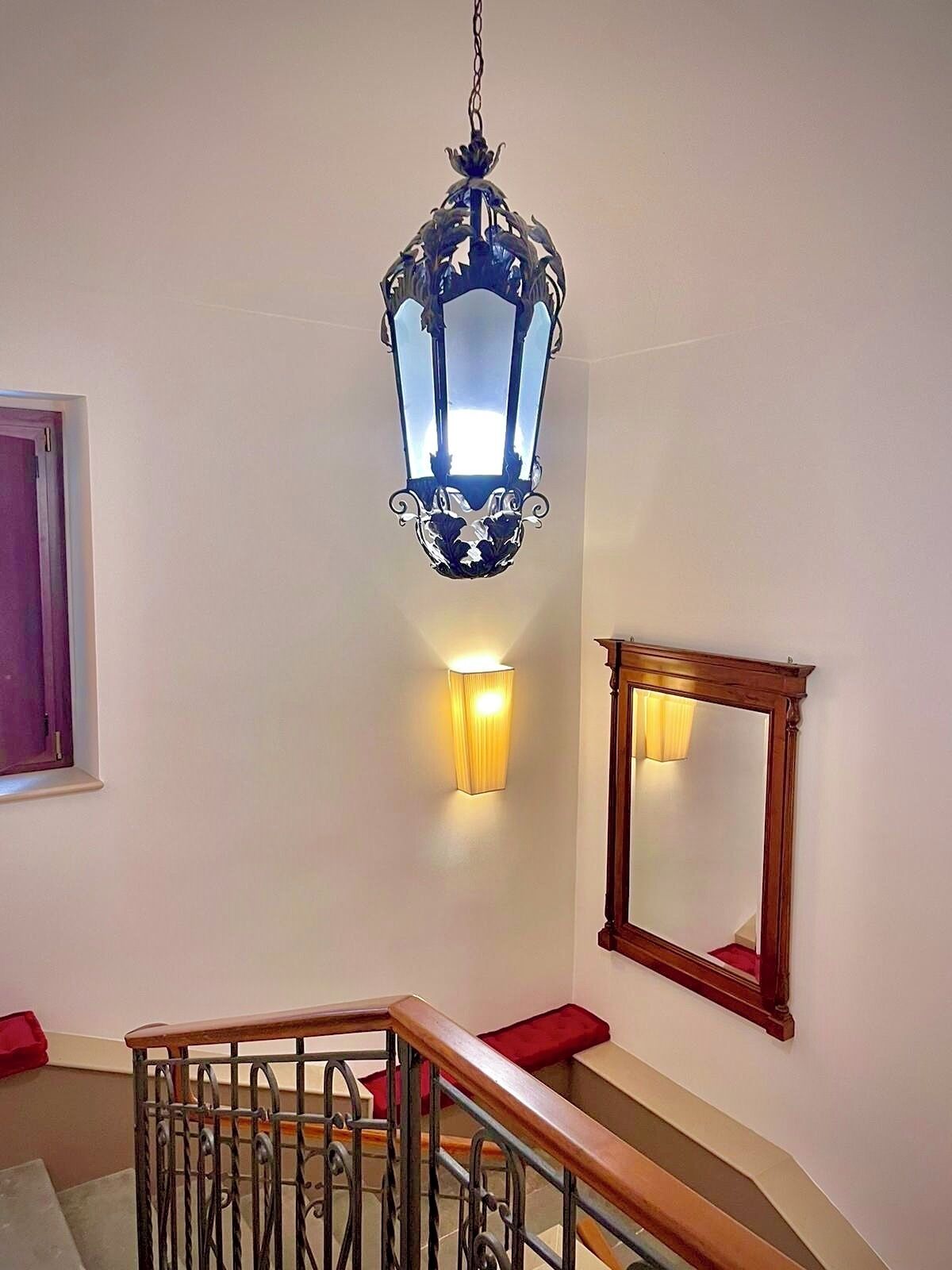 A staircase with a wooden handrail, a metal railing, and a wall-mounted mirror.