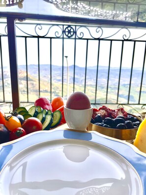 Un balcon doté d’une rambarde en métal et offrant une vue sur un paysage montagneux.