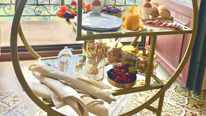Un carrito de desayuno con diversos alimentos y utensilios en un balcón con vistas panorámicas.