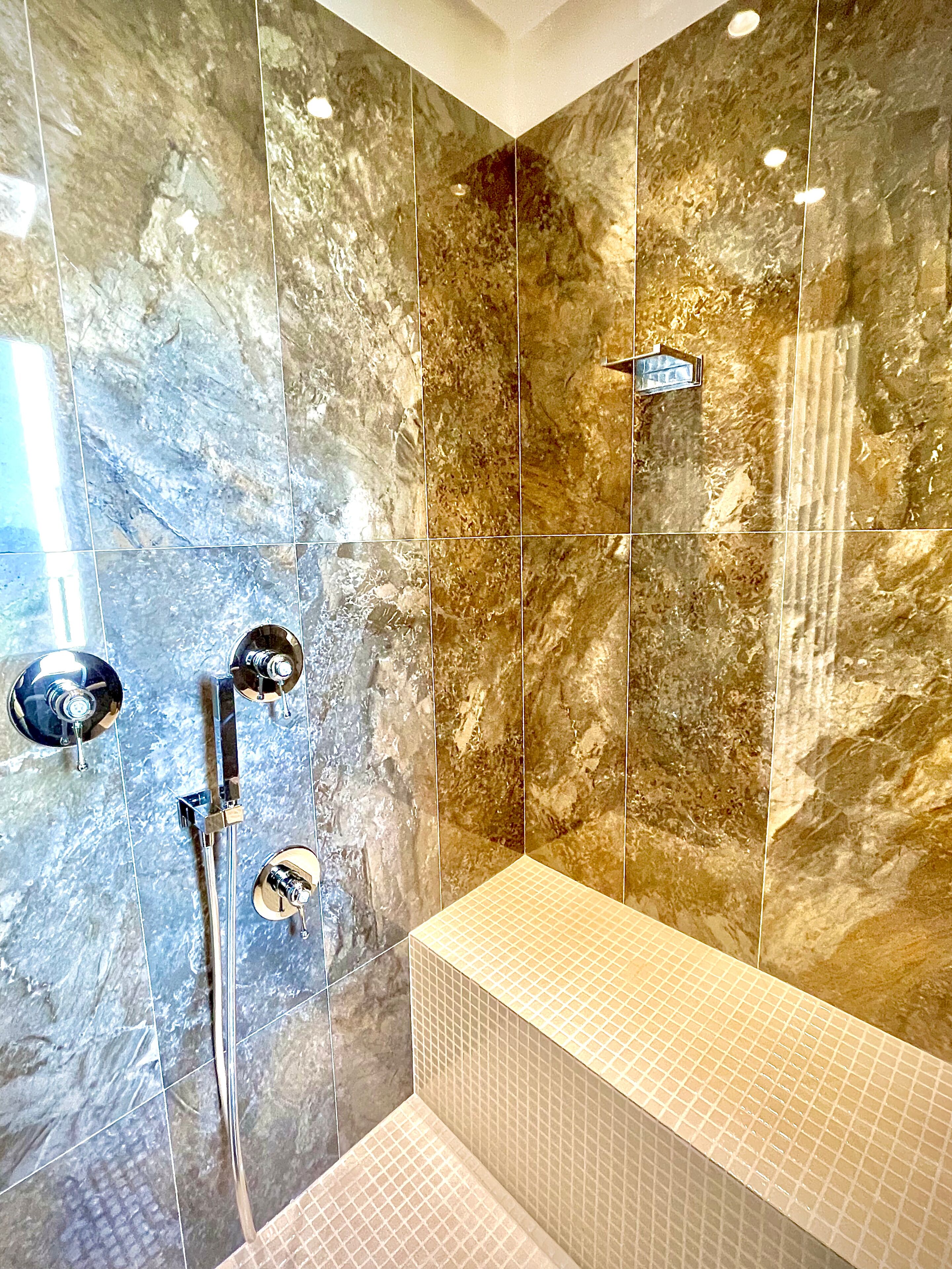 A bathroom with a shower, a bathtub, and a tiled wall.