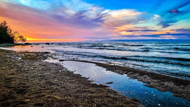 A beach with wet sand and waves, a sunset in the background, and a clear sky. - Happy Valley Spacious Family Townhome.Dog Friendly.Minutes to Blue Mountain (Collingwood)