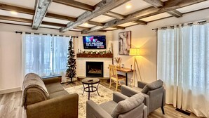 A cozy living room with a fireplace, a television, and a Christmas tree. - Happy Valley Spacious Family Townhome.Dog Friendly.Minutes to Blue Mountain (Collingwood)
