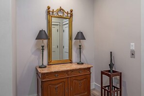 A wooden dresser with two lamps, a mirror, and a small table with an umbrella.