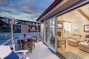 A modern outdoor living area with a glass door leading to a well-lit interior space. - Rivervfront Upper Duplex w/ & Firepit on the Patio (Capitola)