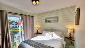 Um quarto com uma cama grande, duas mesas de cabeceira com abajures, uma janela com cortinas e um quadro na parede.