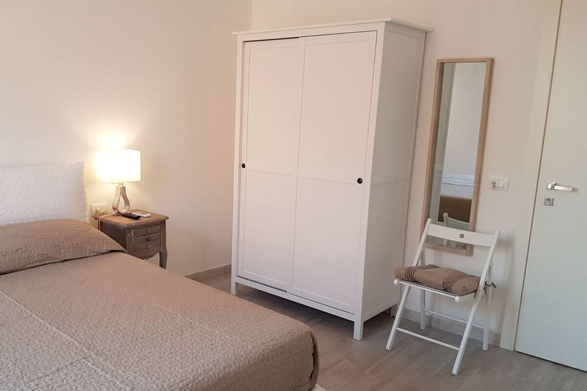 Une chambre à coucher avec un lit, une table de chevet avec une lampe, une armoire et une chaise.