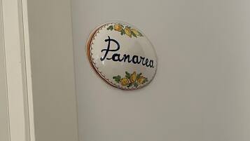 Een wandbord met de naam "Panarea", omgeven door een decoratieve rand met tekeningen van fruit.