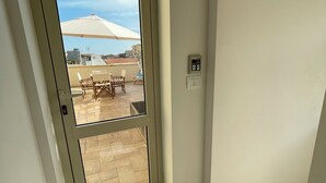 A room with a sliding glass door leading to an outdoor patio area with a table and chairs, a ceiling fan, and a light switch on the wall. - La Coffa (Noto)