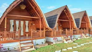 A row of wooden cabins with pitched roofs, each featuring a porch and a small garden area. - Plumeria NP (Penida Island)