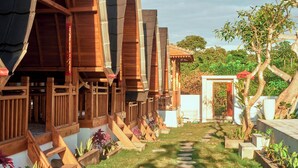 A wooden house with a garden pathway leading to a white door. - Plumeria NP (Penida Island)