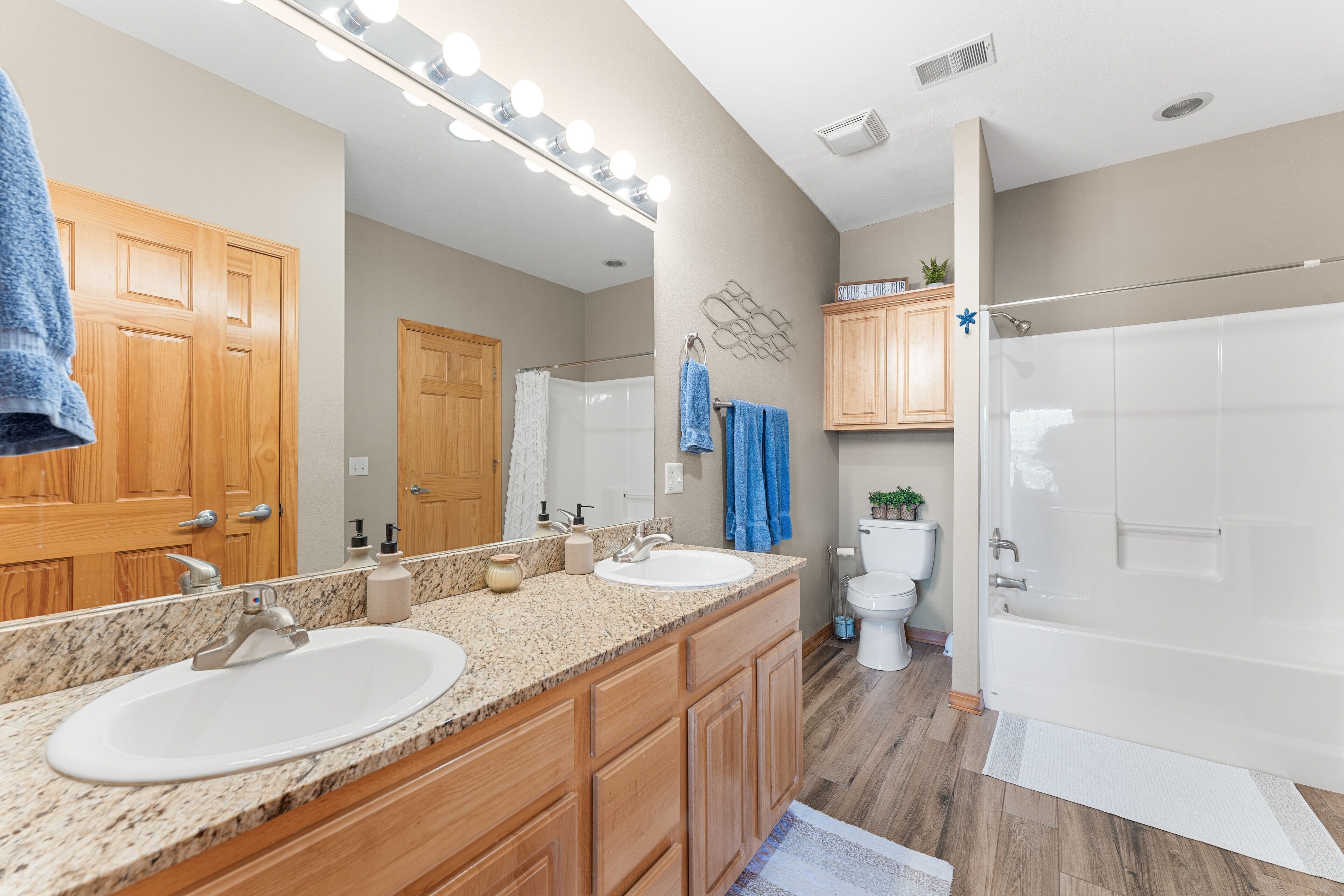 A modern bathroom with two sinks, a large mirror, and a shower.