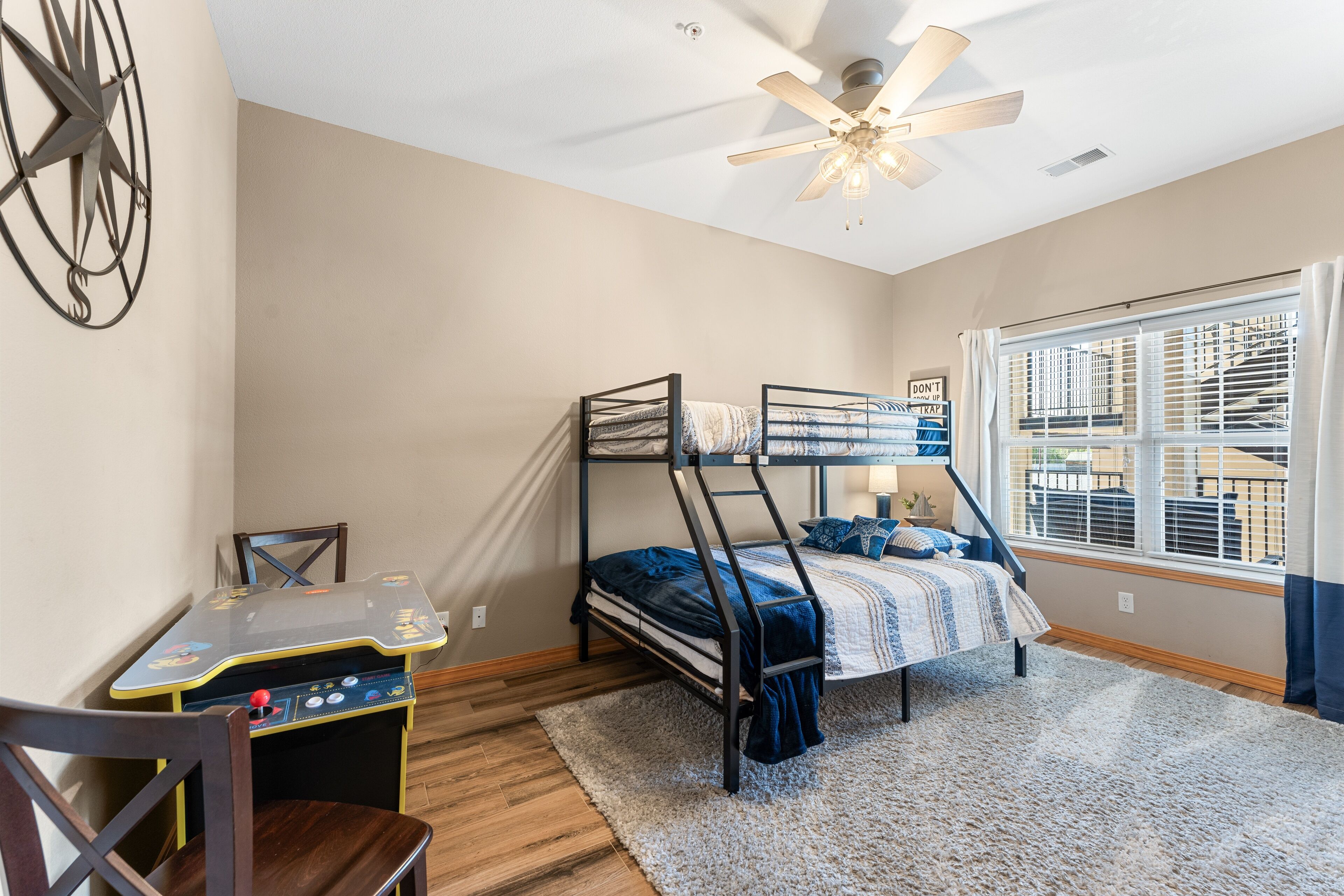 A bedroom with bunk beds, a desk, and a window with blinds.