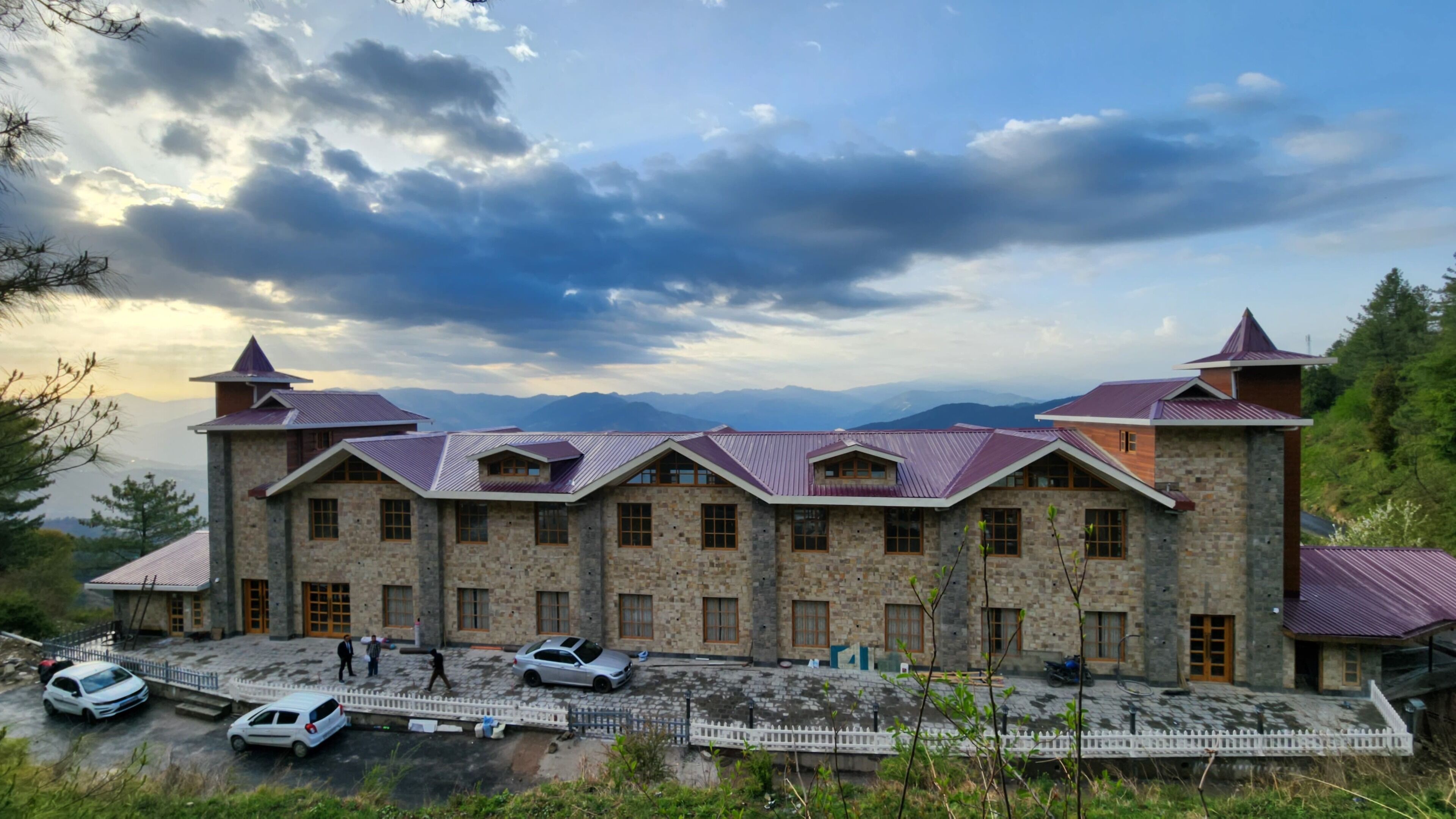 A stone building with multiple windows and a parking area.